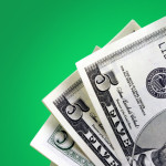Five dollar bills against green background.